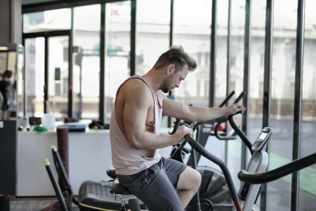 Fit man in gym working out intensely on a stationary exercise bike.